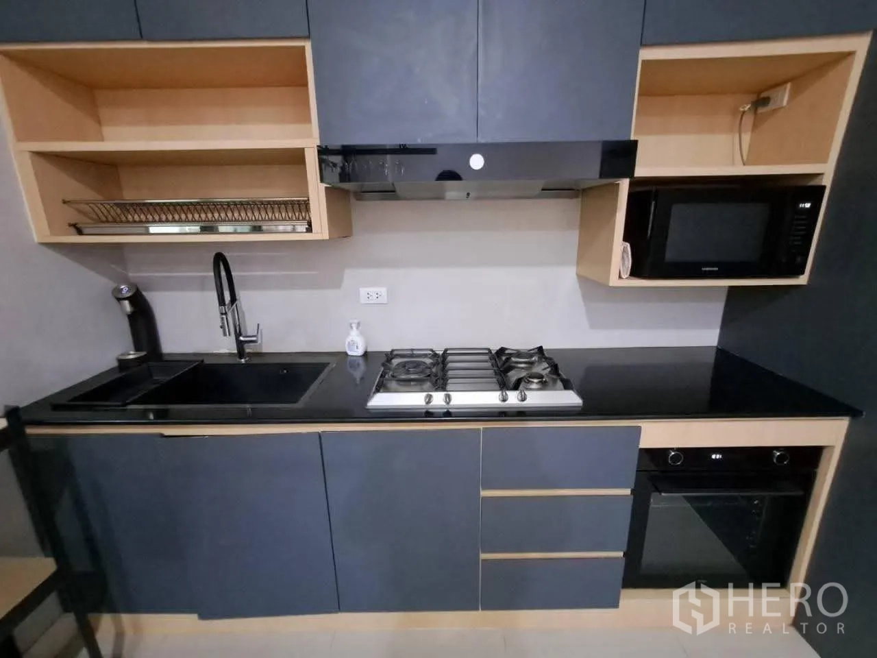Townhouse for rent in Bang Kapi, Bangkok - Built-in kitchen with sink, gas cooktop, oven, microwave and dark cabinets.