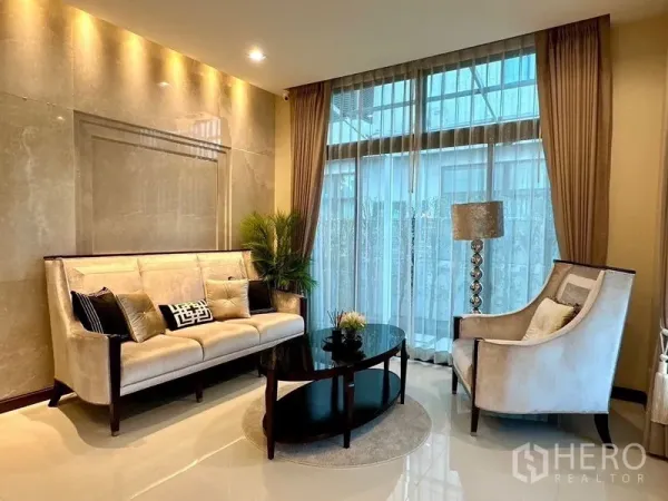 Detached House for rent - Cozy living corner with cream sofa, armchair, floor-to-ceiling curtains and warm lighting.