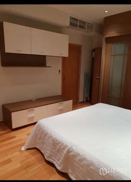 คอนโด ให้เช่า - มุมห้องนอนที่มีตู้เก็บของ ชั้นวางทีวี และพื้นไม้