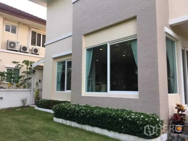 Detached House for sale in Bang Kruai, Nonthaburi - Ground-floor corner with large picture windows, curtains and a small landscaped garden.