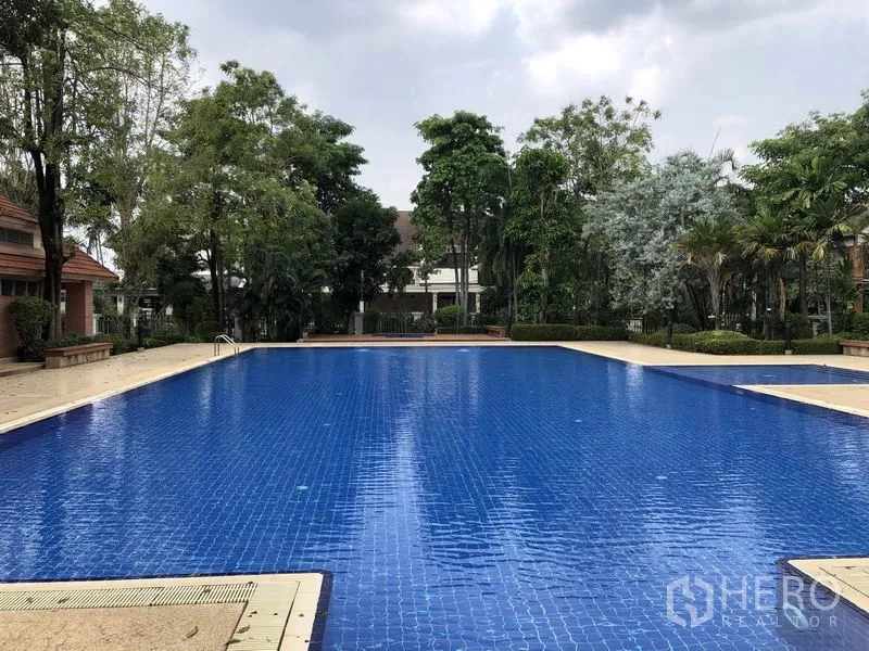 Detached House for rent in Saphan Sung, Bangkok - Outdoor swimming pool with blue tiles, tree-lined deck and landscaping.