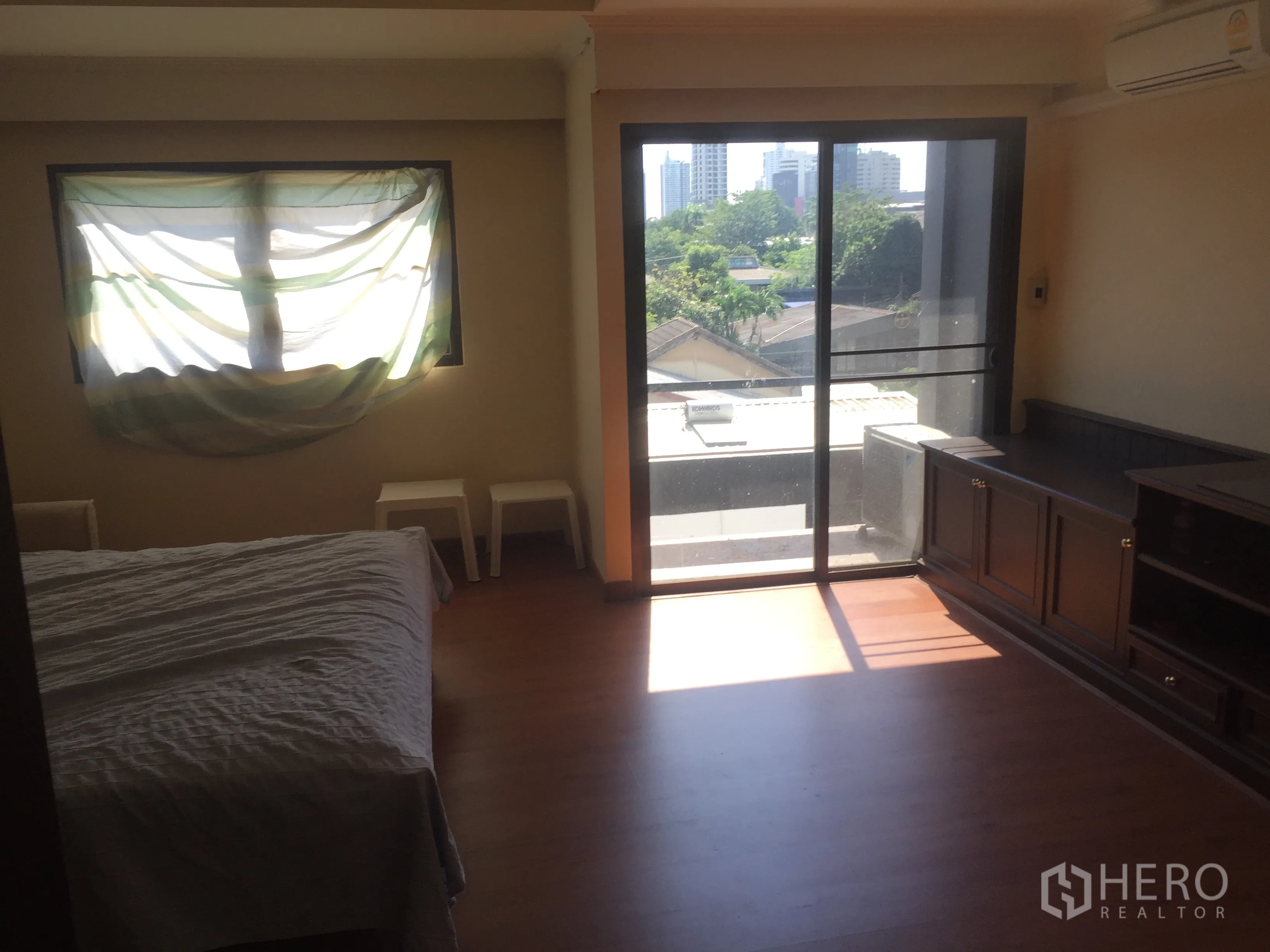 Townhouse for rent in Khlong Toei, Bangkok - Bedroom with built-in cabinetry and balcony access, with city views in the distance.