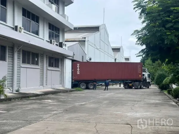 Warehouse for rent in Mueang Samut Prakan, Samut Prakan - Container truck at warehouse loading dock with wide driveway and greenery in Samut Prakan.
