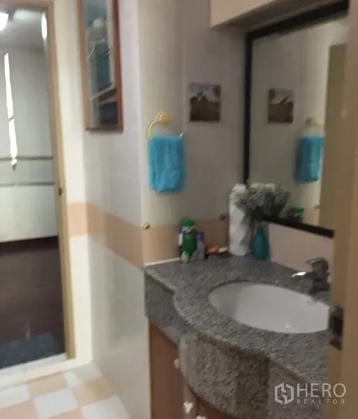 Condominium for rent in Watthana, Bangkok - Clean tiled bathroom featuring a granite countertop vanity, large mirror and storage cabinets.