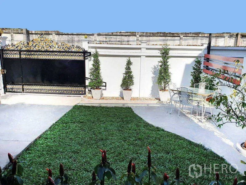 Detached House for rent in Phra Khanong, Bangkok - Private small garden with lawn, potted trees, patio seating and a decorative gate.