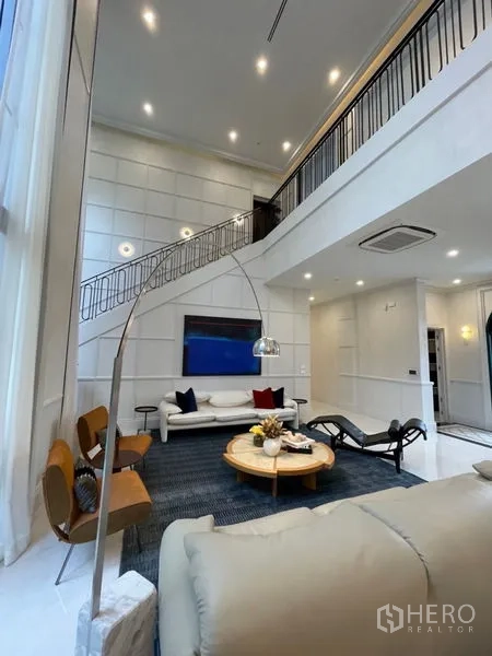Detached House for sale in Suan Luang, Bangkok - Double-height living room with mezzanine, recessed lighting and a sleek staircase.