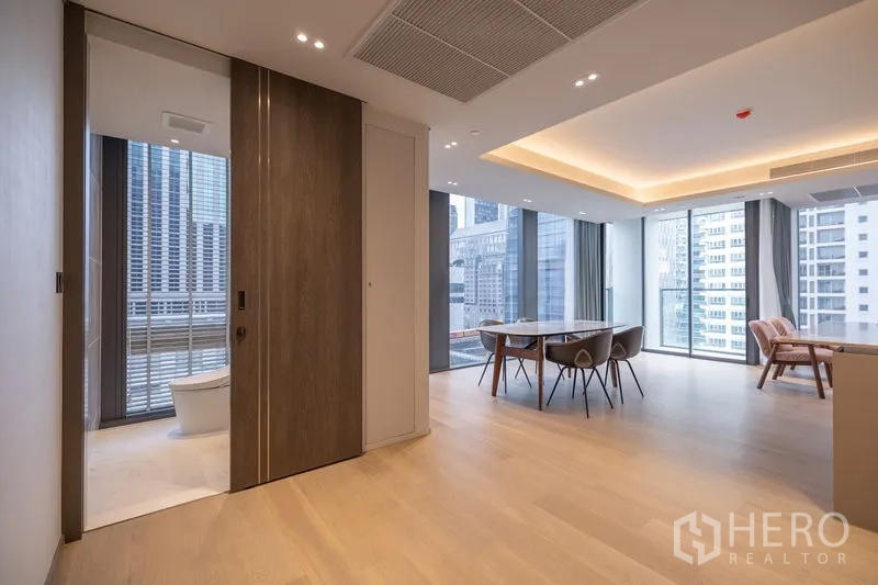 Condominium for rent in Pathum Wan, Bangkok - Hallway from living area to bathroom with city views through glass.