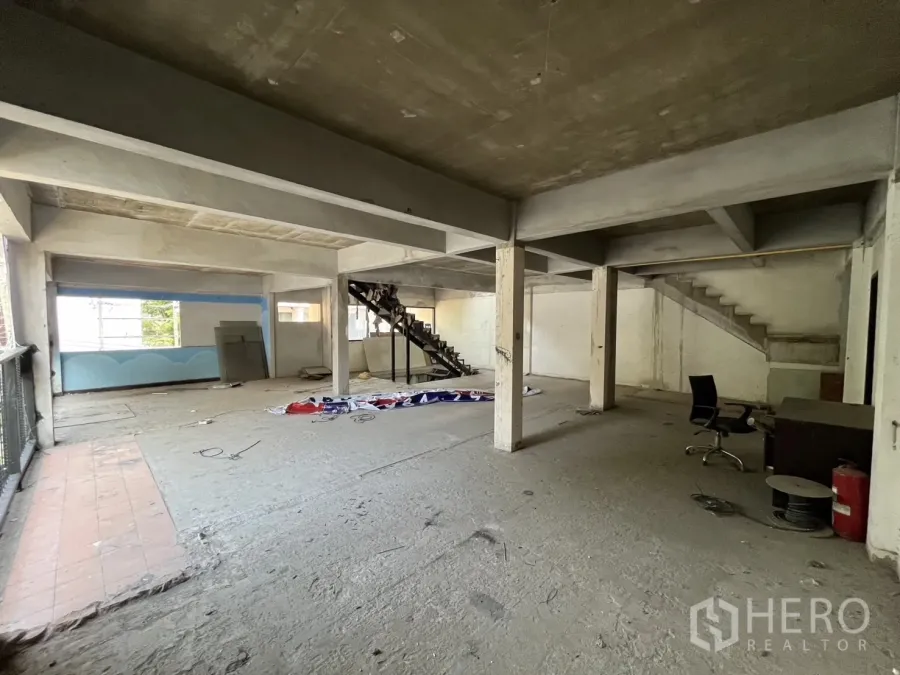 Retail Space for rent in Watthana, Bangkok - Unfinished open-plan retail floor with concrete columns, wide windows and a metal staircase.