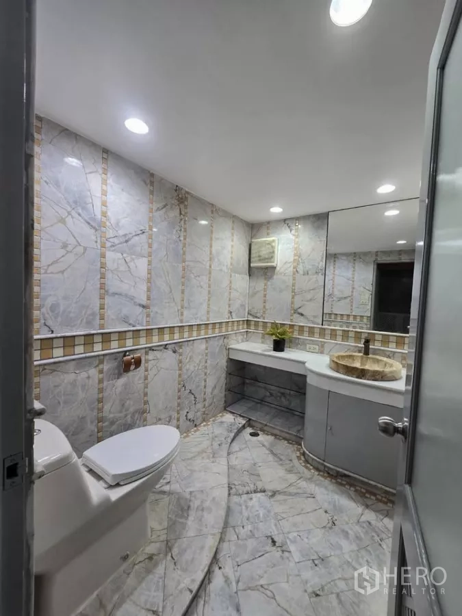 公寓 出租在Pathum Wan, Bangkok - 浴室铺大理石墙面，带台盆与坐便器。