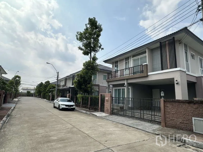 Detached House for sale in Sai Mai, Bangkok - Quiet residential street view with the house and a parked car in front.