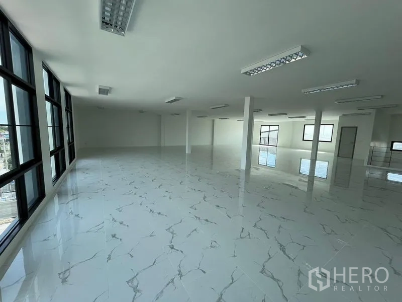 Warehouse for rent in Bang Sao Thong, Samut Prakan - Bright open-plan office floor with marble-look tiles, tall windows and LED lighting inside the warehouse.