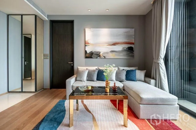 Condominium for rent in Khlong Toei, Bangkok - Contemporary living room with L-shaped sofa, large window and abstract art