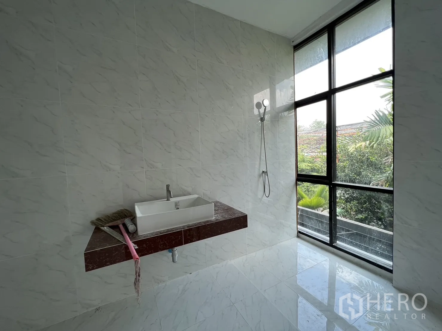 Detached House for rent or sale in Phra Khanong, Bangkok - Bathroom with marble tiles, large window, wall-mounted vanity and shower.
