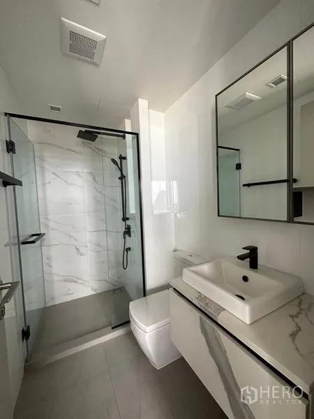 Condominium for rent in Phra Khanong, Bangkok - Sleek bathroom featuring a glass-enclosed shower, rain showerhead and marble vanity.