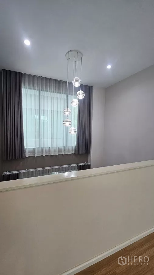 Townhouse for rent in Saphan Sung, Bangkok - Upper landing with modern globe pendant lights and a large window.