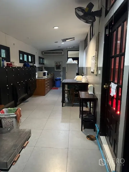 Shophouse for rent in Phra Khanong, Bangkok - Back-of-house pantry corridor with lockers, microwave, refrigerator and exterior door.