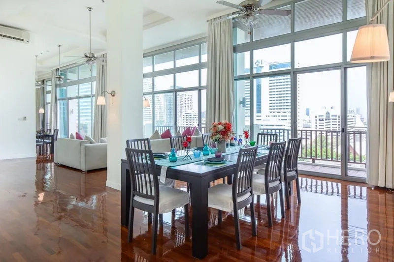 Condominium for rent in Bang Rak, Bangkok - Dining space opening to a balcony with panoramic Bangkok skyline through tall glass windows.
