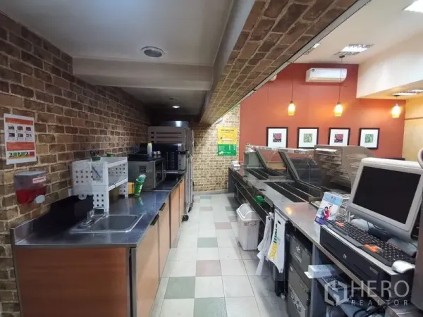 Shophouse for rent in Bangkok - Commercial prep line with brick accent walls, pendant lights, and stainless counters.