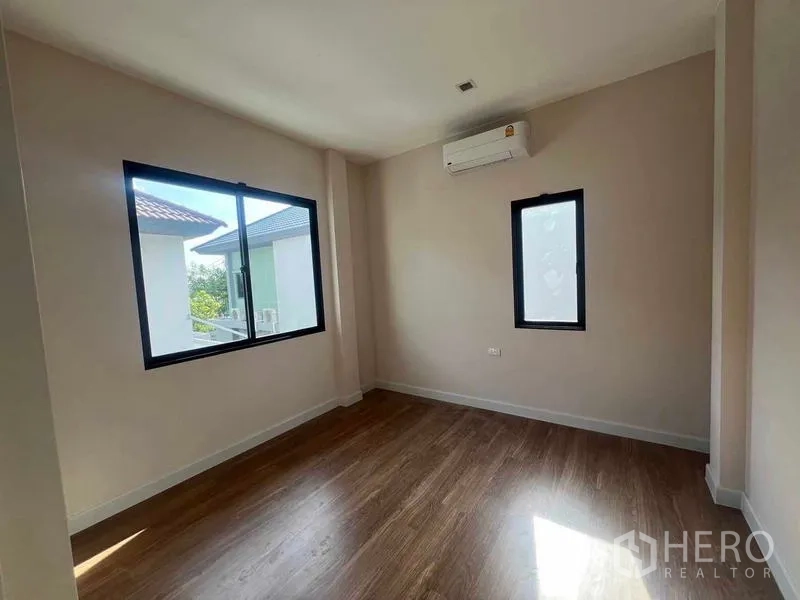 Detached House for sale in Bang Kruai, Nonthaburi - Second bedroom with wood flooring, split-type air conditioner and two windows for cross ventilation.