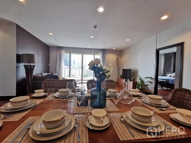 Condominium for rent or sale in Khlong Toei, Bangkok - Dining table elegantly set for six, looking toward the living area and balcony doors.