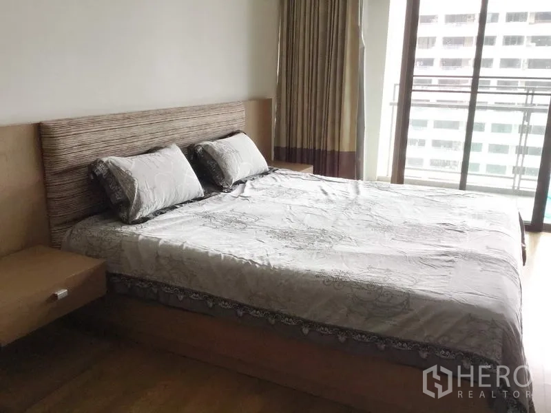 คอนโด ให้เช่าในWatthana, Bangkok - ห้องนอนหลักเตียงคิงส์ เฮดบอร์ดไม้ หน้าต่างกระจกเต็มบานและประตูออกไประเบียงวิวเมือง