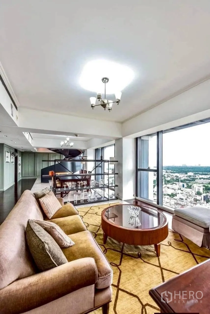 Condominium for rent in Sathon, Bangkok - Duplex living room with sofa and coffee table, full-height windows and panoramic skyline and river view.