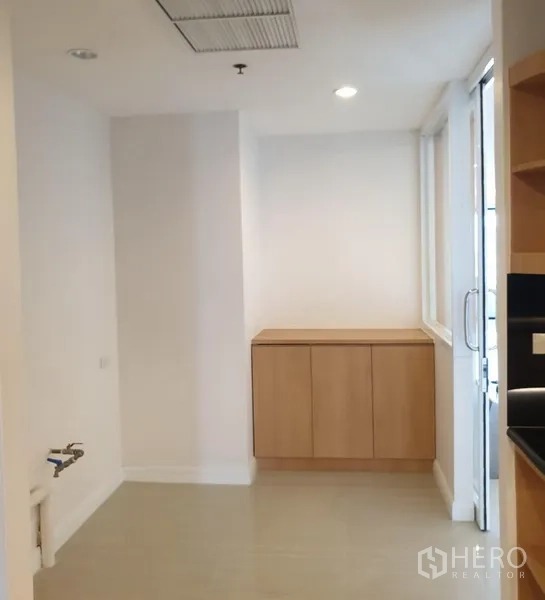 Condominium for rent in Watthana, Bangkok - Utility or pantry area with white walls, built-in cabinet and sliding glass door to a service balcony.