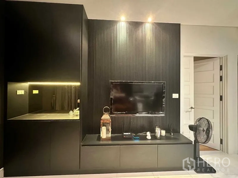 Condominium for sale in Khlong Toei, Bangkok - Contemporary living area with black feature wall and mounted TV unit.