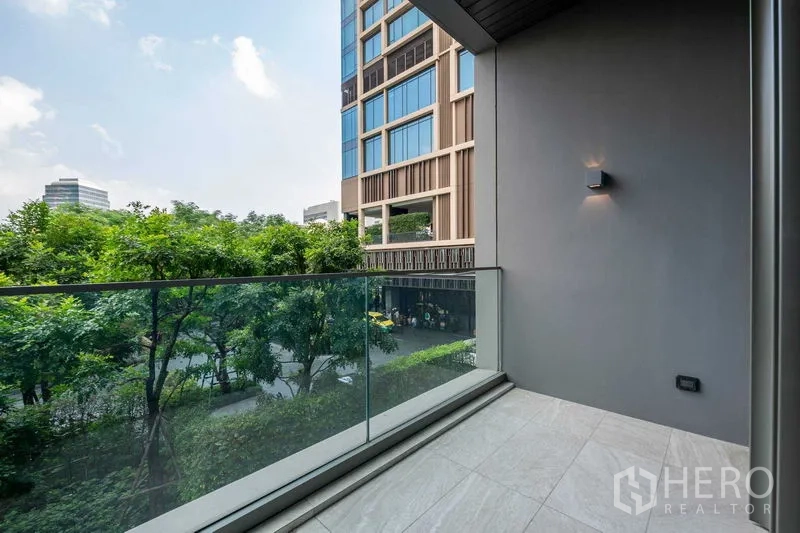 公寓 出售在Pathum Wan, Bangkok - 私家阳台玻璃护栏，俯瞰树木与现代建筑。