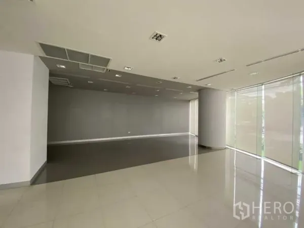 Retail Space for rent - Open‑plan retail floor with grey accent wall and tall windows with blinds.