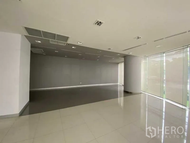 Retail Space for rent - Open‑plan retail floor with grey accent wall and tall windows with blinds.
