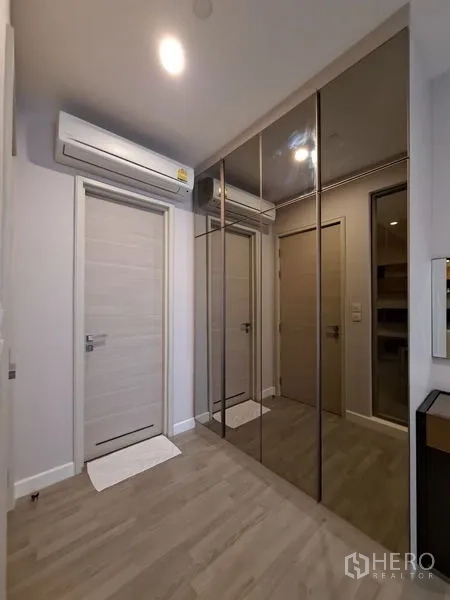 Condominium for rent in Bang Rak, Bangkok - Hallway with mirrored wardrobes, air conditioner, and light wood doors.