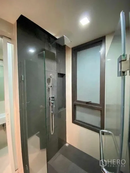 Condominium for rent in Khlong Toei, Bangkok - Close-up of rain shower and handheld set behind a glass door next to a window.