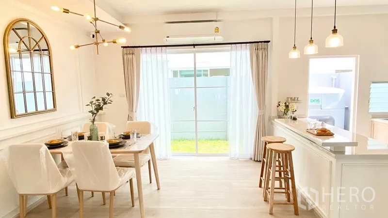 Townhouse for rent in Prawet, Bangkok - Dining area beside large sliding glass door to a small lawn, pendant lighting and a breakfast bar with stools.