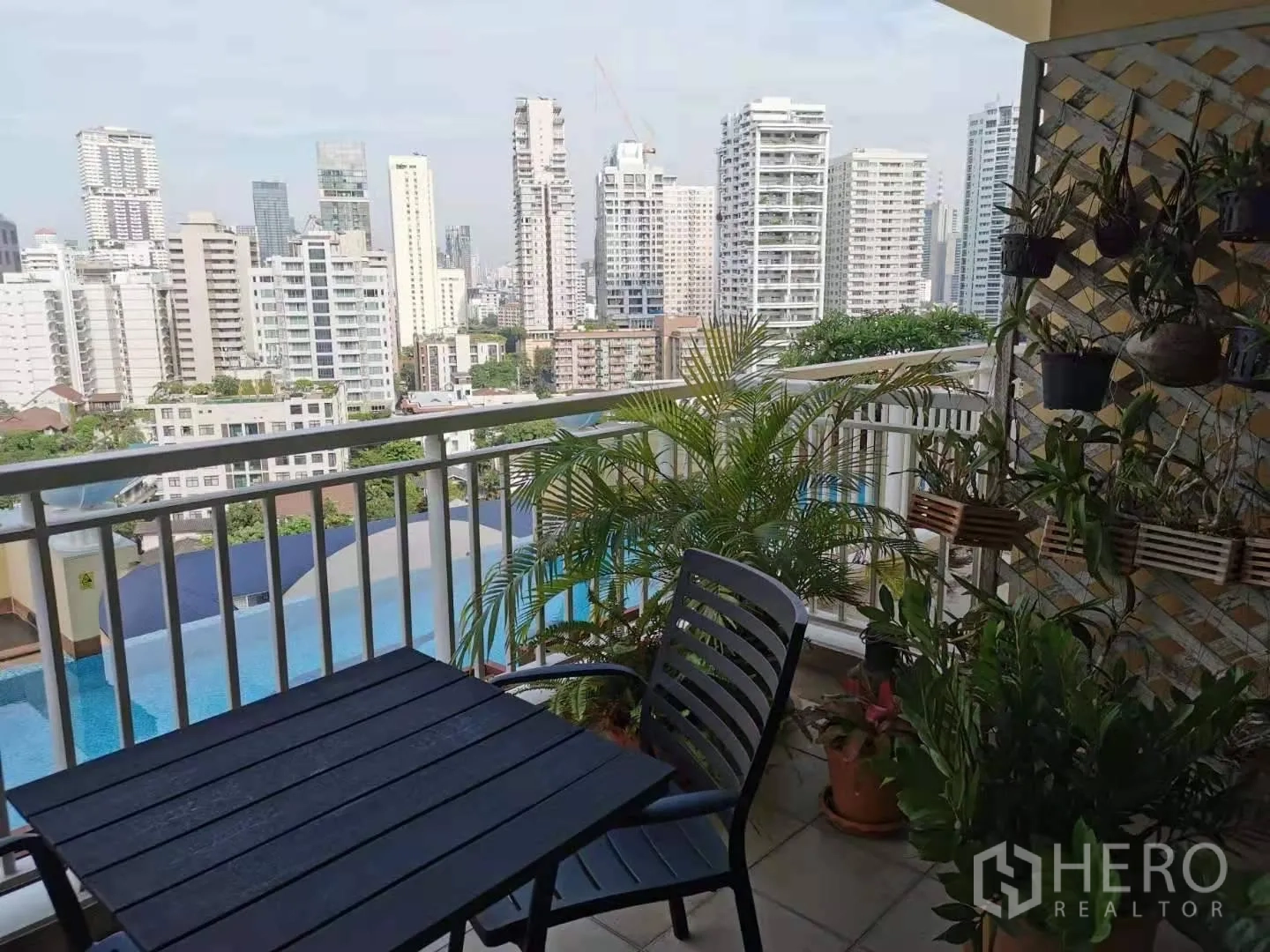 คอนโด ให้เช่าในKhlong Toei, Bangkok - ระเบียงมีต้นไม้กระถางและชุดโต๊ะเก้าอี้ มองสระว่ายน้ำและวิวเมือง