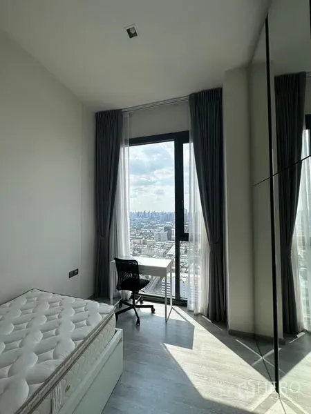 Condominium for rent in Phra Khanong, Bangkok - Cozy bedroom with a desk by a full-height window and mirrored wardrobe, offering panoramic city views.