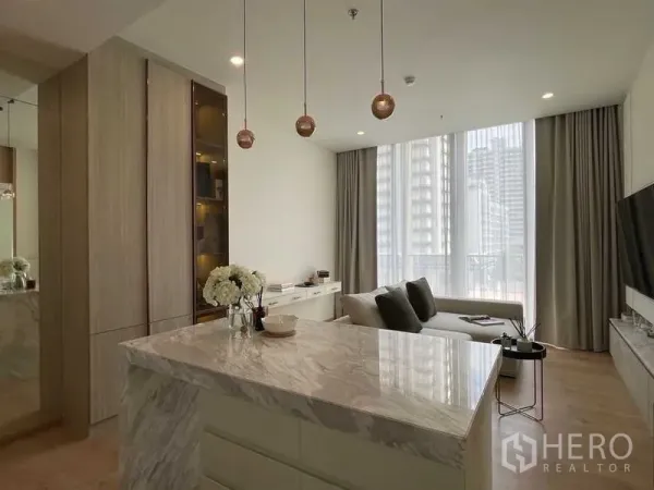 Condominium for sale in Watthana, Bangkok - Polished marble island with copper pendant lights facing a bright lounge and full-height windows.