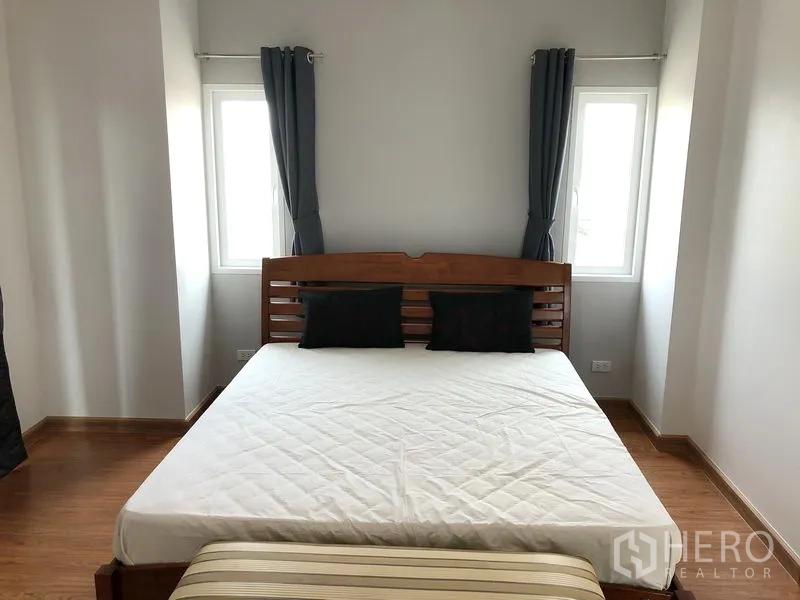 บ้าน ให้เช่าหรือขายในHuai Khwang, Bangkok - ห้องนอนมุมบ้าน เตียงไม้ หน้าต่างสองด้านและผ้าม่านโทนเรียบ