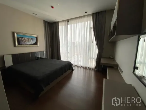 Condominium for rent in Khlong Toei, Bangkok - Second bedroom with king bed, built-in desk and large windows providing a city outlook.