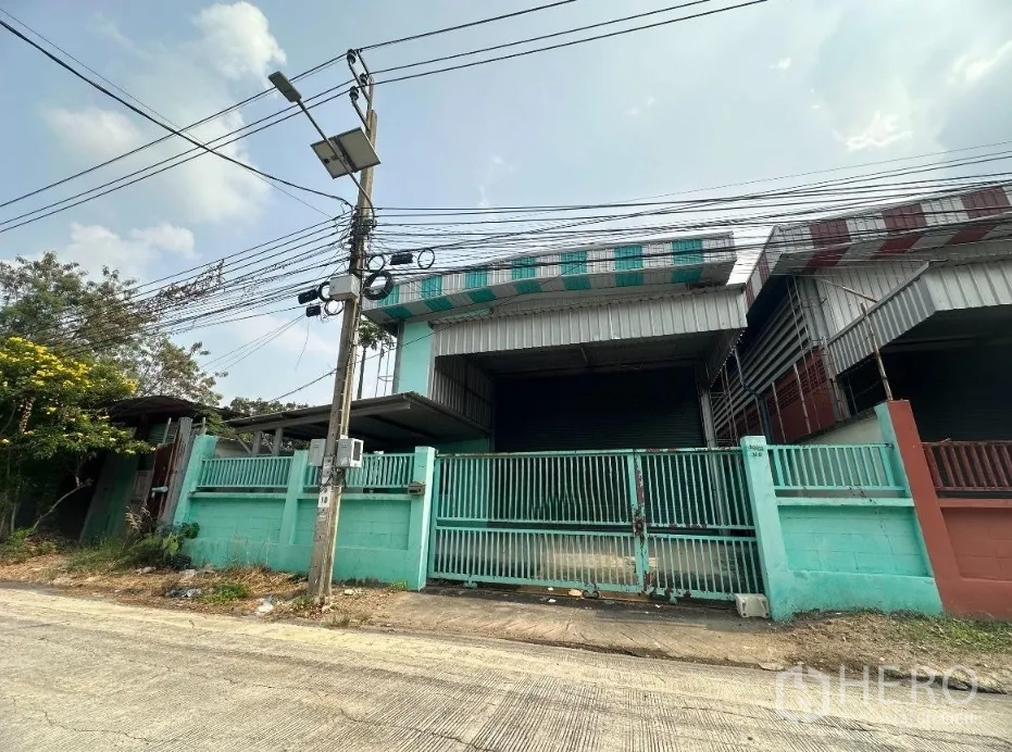 Warehouse for rent in Pak Kret, Nonthaburi - Street-facing warehouse exterior with gated entrance and roller shutter loading area.