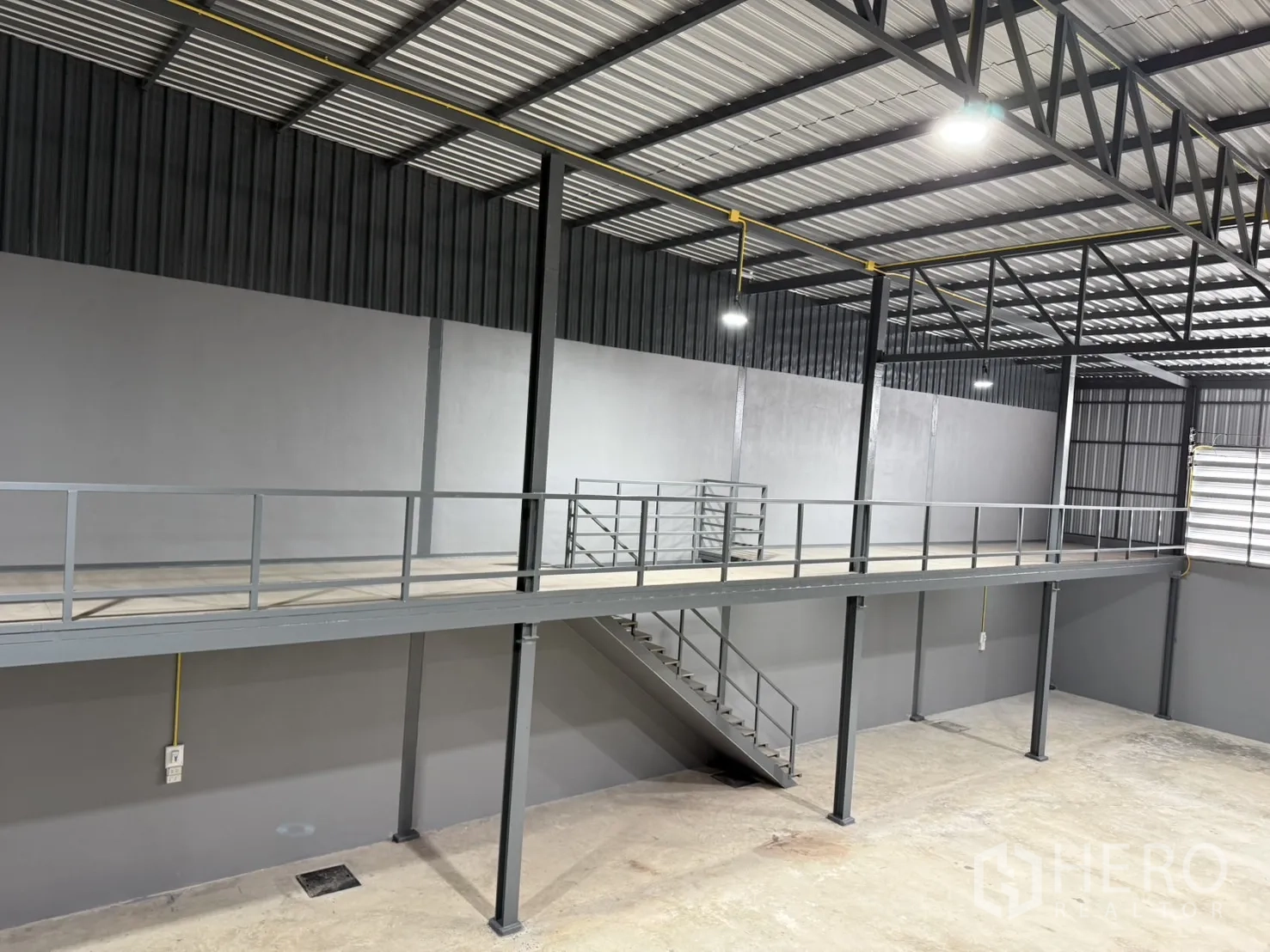 Warehouse for rent in Lam Luk Ka, Pathum Thani - Elevated mezzanine walkway with guardrails and stairs inside the warehouse.
