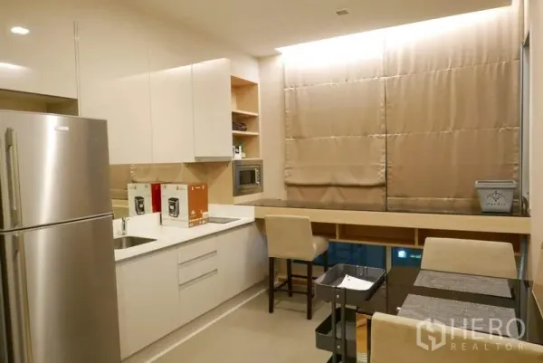 公寓 出租在Ratchathewi, Bangkok - 现代厨房，白色橱柜，不锈钢冰箱，嵌入式微波炉与就餐吧台。