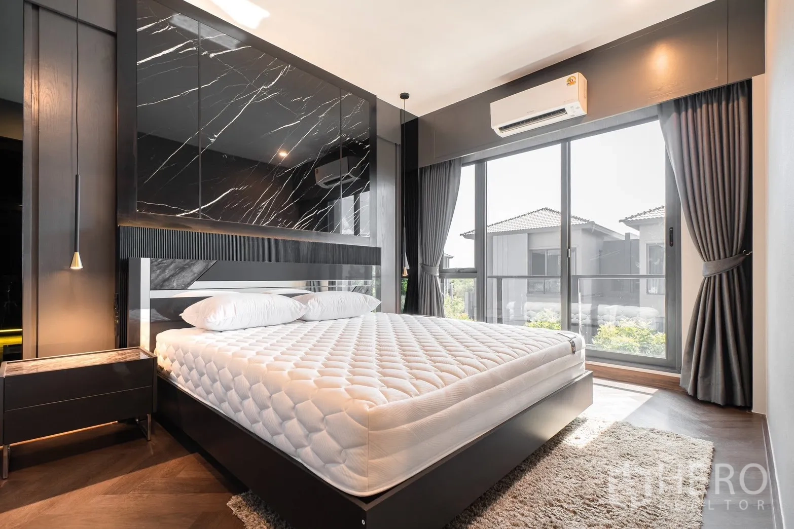Detached House for rent or sale in Prawet, Bangkok - Master bedroom with dark marble headboard, pendant lights and balcony windows