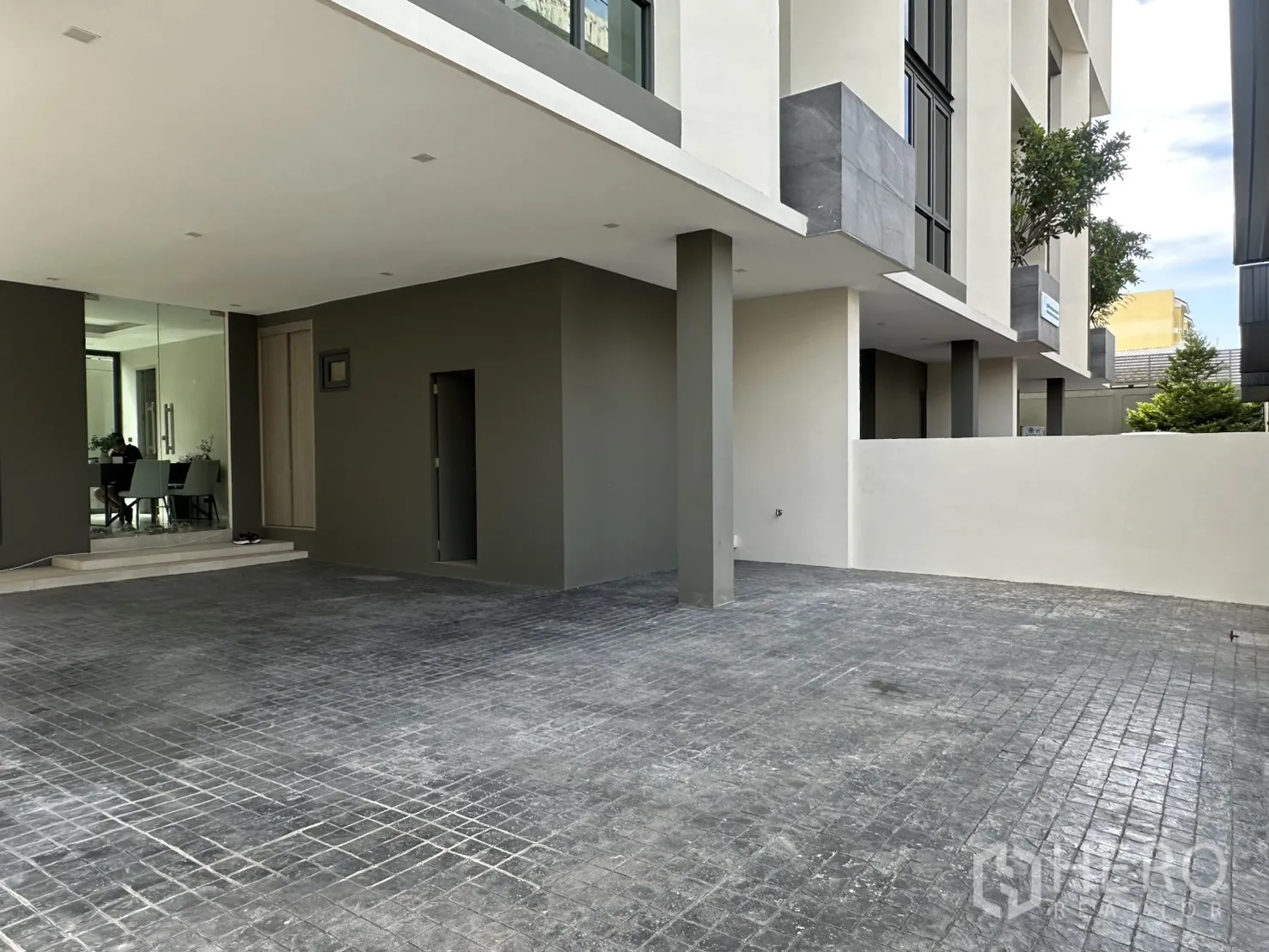 家庭办公室 for rent or sale in Suan Luang, Bangkok - 一层入口设玻璃门，前方为铺装停车区域。