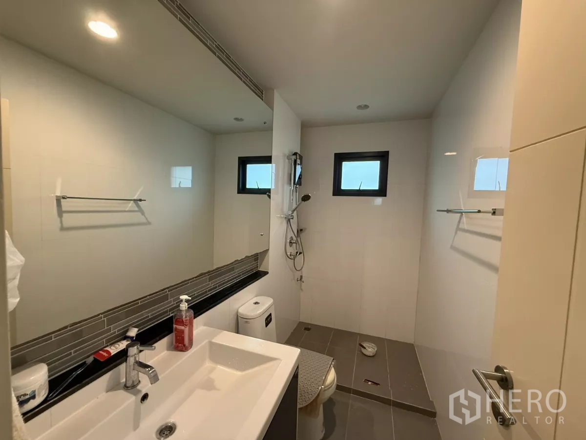 Detached House for rent in Bang Kapi, Bangkok - Bathroom with wide vanity, toilet, and separate shower area with small windows.