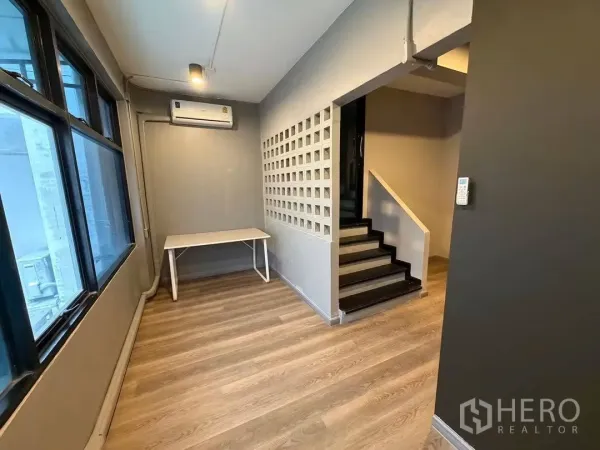 Home Office for rent in Watthana, Bangkok - Compact workspace with air conditioner, table and stairs nearby.