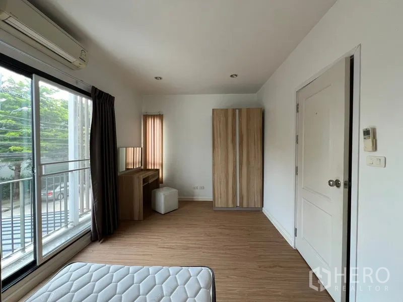 Townhouse for rent in Bang Kapi, Bangkok - Bedroom view showing wardrobe, dressing table and balcony access.