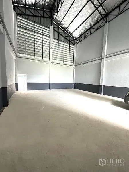 Warehouse for rent in Khlong Luang, Pathum Thani - High-ceiling storage hall with steel truss roof, louvered panels and concrete floor.