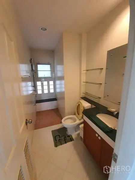 独立式住宅 出租在Lat Krabang, Bangkok - 浅色调浴室，含盥洗台、置物镜、坐便和靠磨砂窗的淋浴区。