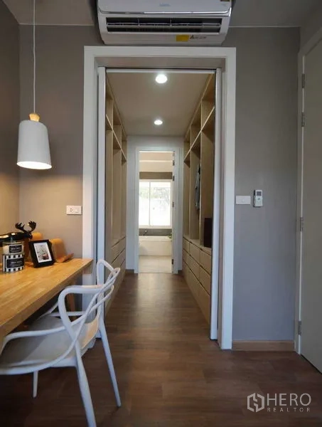 Townhouse for rent in Watthana, Bangkok - Hallway walk-in closet with built-in wardrobes and study nook beneath pendant light.